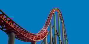 Rollercoaster track rising and falling against a blue sky, representing KiwiSaver market volatility and global events.