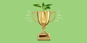 Gold trophy cup on a green background with a plant growing from the top 