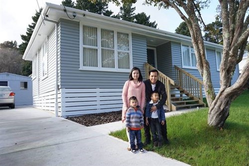 Parents and two children outside their home, representing buying or owning a house.